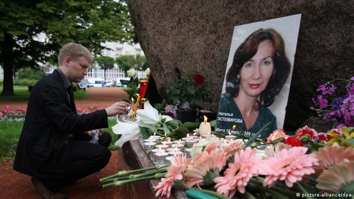 Photo with a portrait of Natalya Estemirova, in front of which there are flowers and candles in memory of her