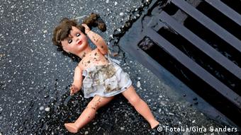 Broken doll on the asphalt